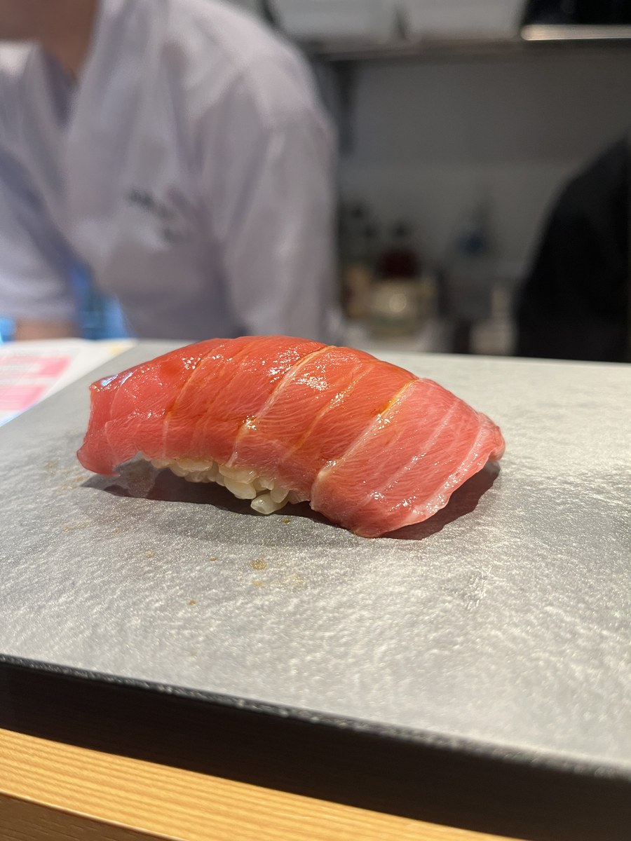 A piece of chū-toro (medium-fatty tuna) nigiri on a stone plate at Akira