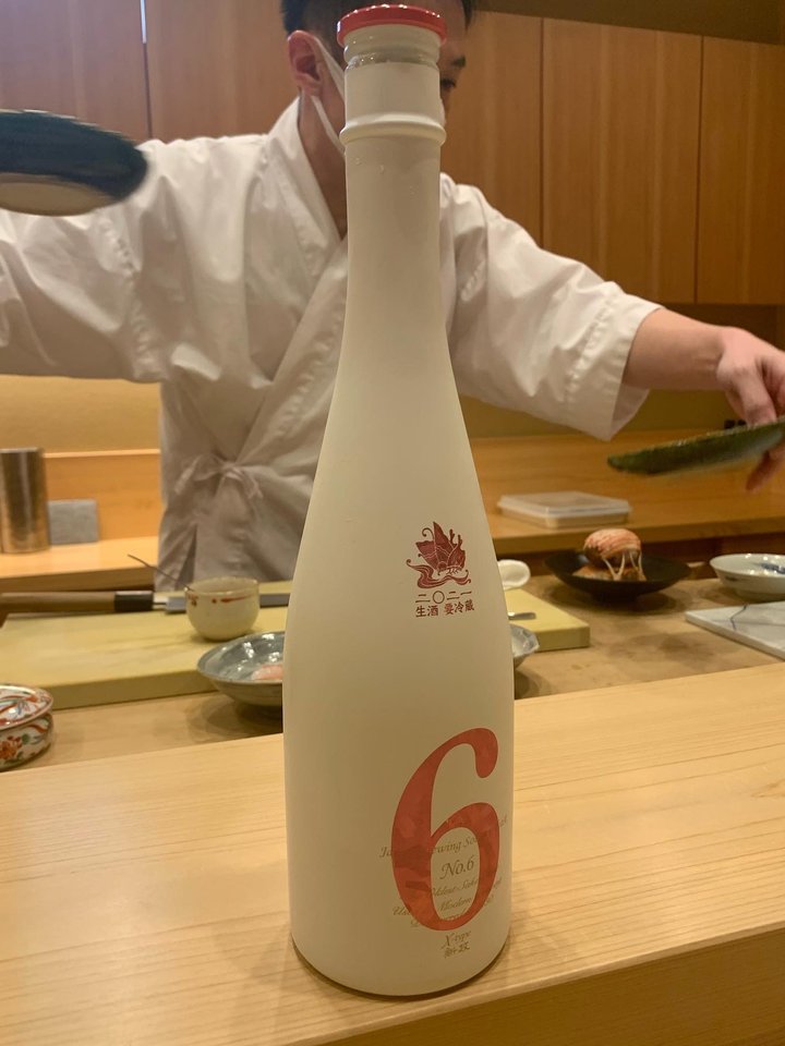 A Christmas special edition of Aramasa No. 6 X-type, white bottle with a red 6 and a festive crest, the chef behind the counter