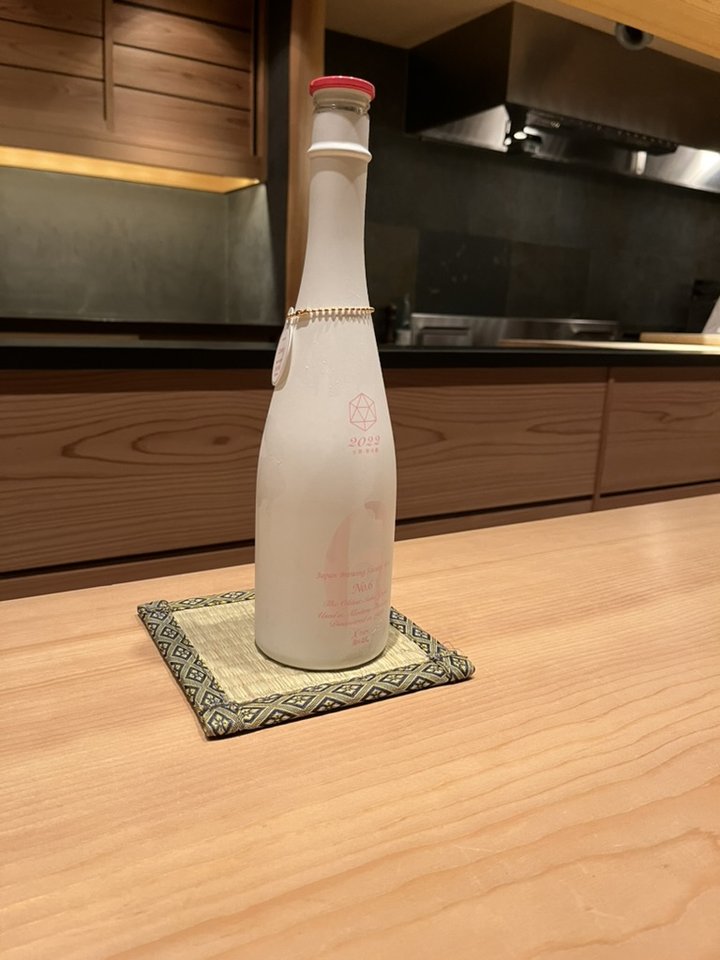 An Aramasa No. 6 X-type bottle, frosted white with a pink 6, on a counter