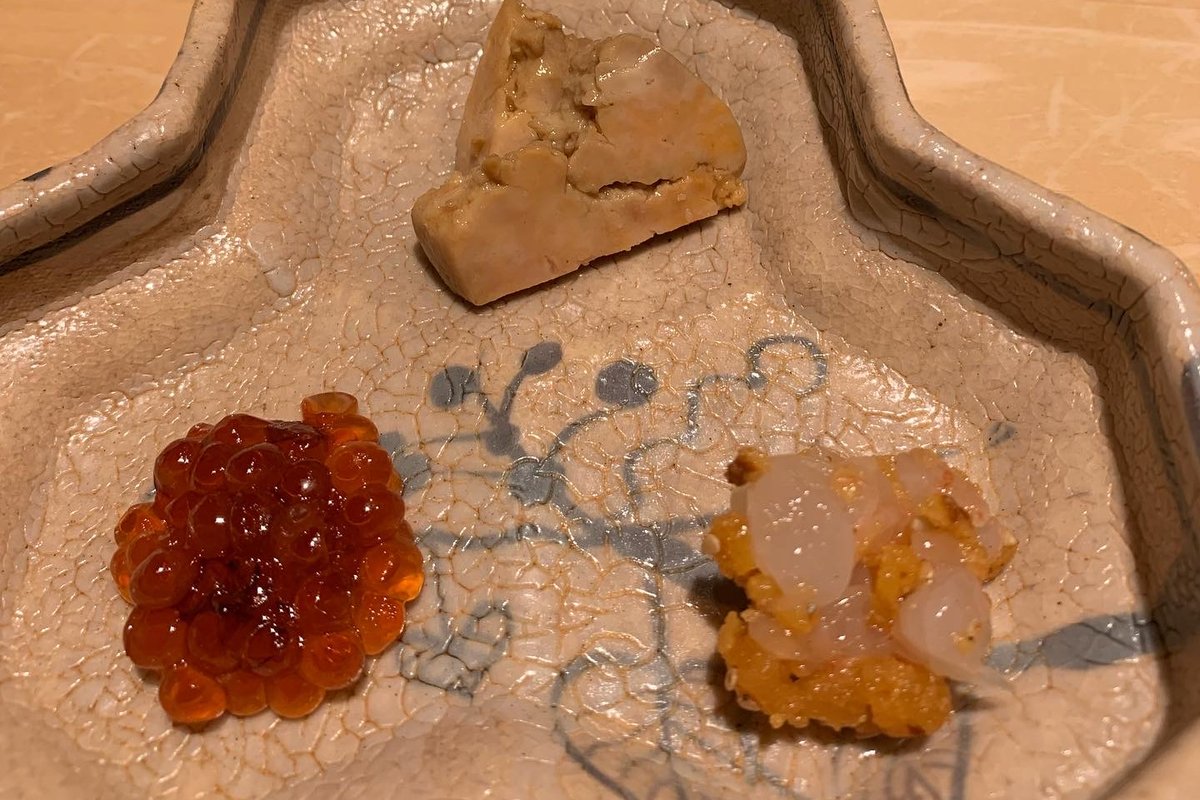 A three-piece otsumami assortment on a star-shaped plate: salmon roe, a wedge of liver, and orange roe with translucent pieces