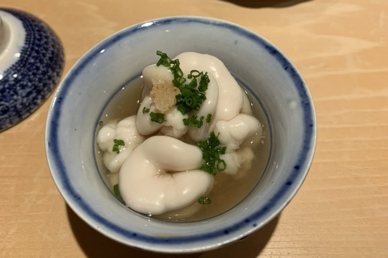 Cod milt in a blue-and-white bowl of light broth, topped with chopped chives
