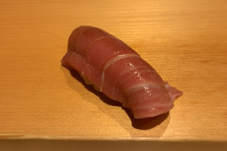 A marbled toro nigiri, fatty tuna, on the wooden counter