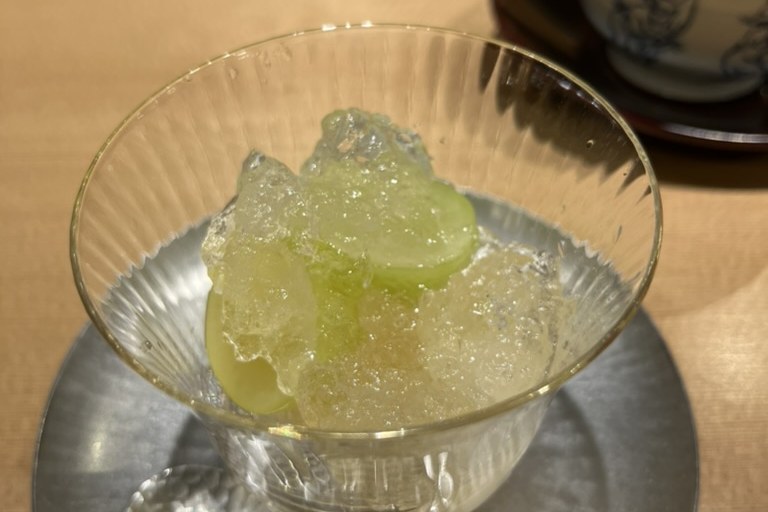 Muscat grapes set in a glittering crushed jelly, in a ribbed glass cup on a hammered silver plate