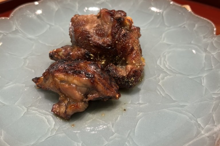 Pieces of dark, glazed grilled snapping turtle on a pale celadon plate