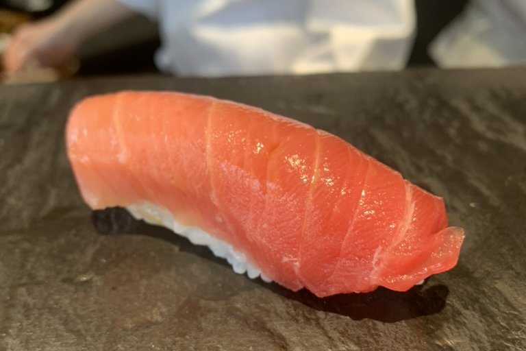 A chūtoro nigiri on a slate plate, the medium-fatty tuna pale pink with fine marbling