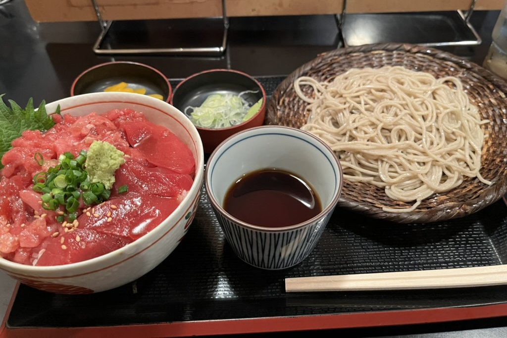 A maguro don of akami and minced tuna beside a basket of cold zaru soba with dipping sauce