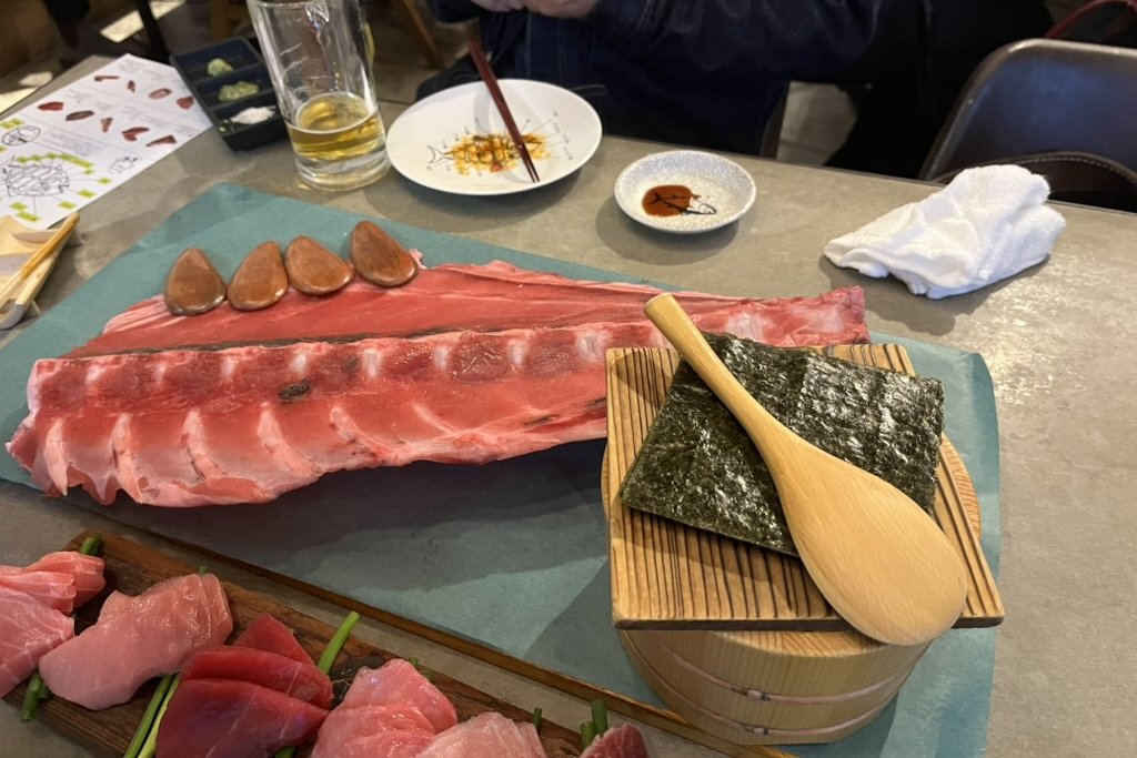 A long rack of tuna belly bones with nori, a rice tub, and a paddle for making your own hand rolls