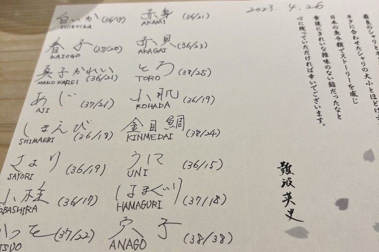 A handwritten card listing each sushi topping with two temperatures, signed by the chef