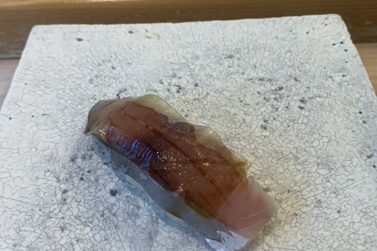 A cured mackerel nigiri with a translucent slice of kombu laid over it