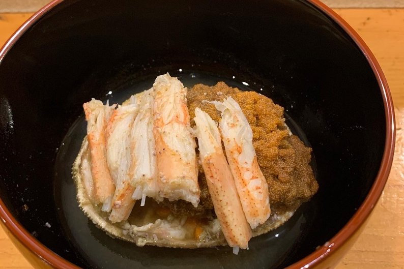 A black lacquer bowl of snow crab — picked leg meat with the crab's own miso and orange roe