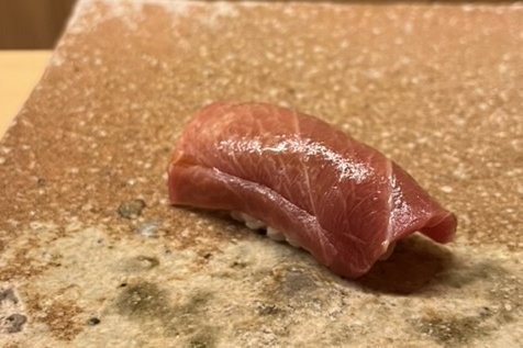 A chutoro nigiri on a reddish stone plate