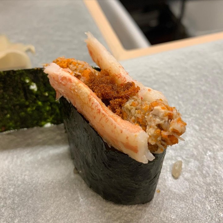 A crab gunkan, nori-wrapped sushi topped with snow crab leg, innards and orange roe