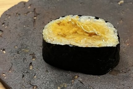 A nori-wrapped uni roll made with premium pale-gold sea urchin
