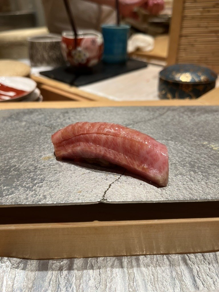 A piece of ō-toro fatty tuna nigiri on a stone plate