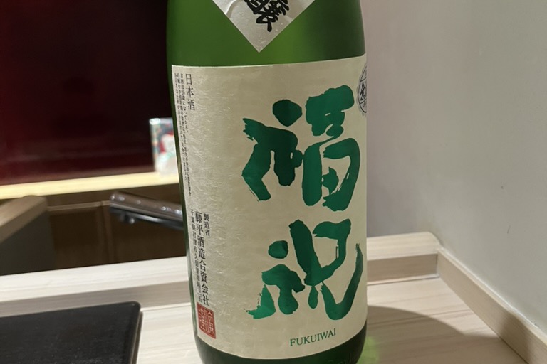 A green bottle of Fukuiwai junmai ginjo sake on the counter
