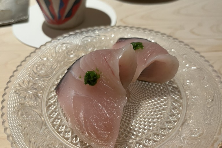 Slices of sawara, Spanish mackerel, on a cut-glass plate, each dotted with green