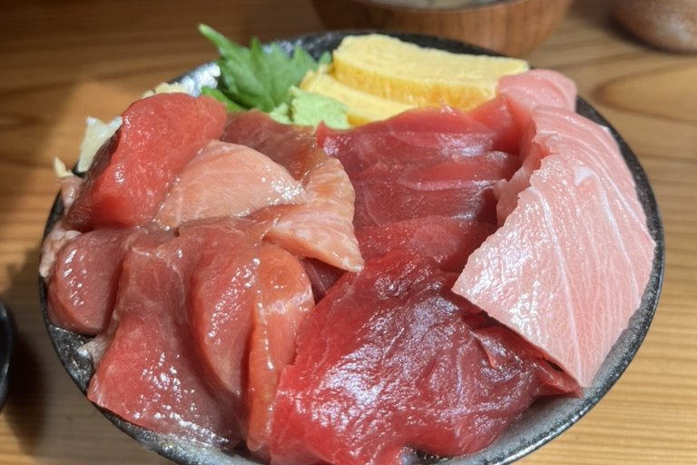 A bowl of rice heaped with assorted tuna cuts, tamago and shiso