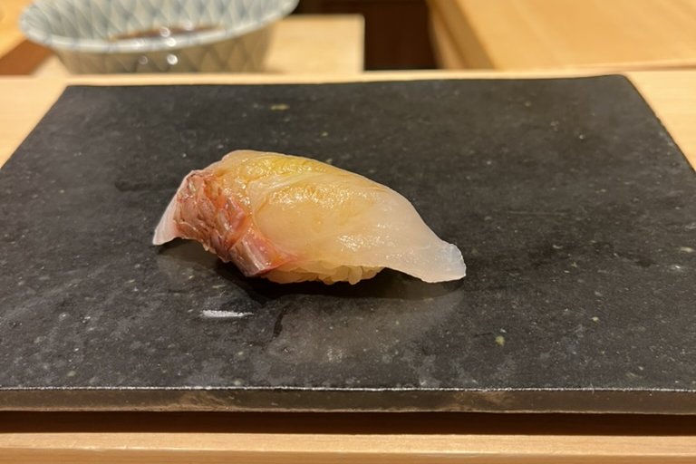 A white-fish nigiri with its red skin lightly seared