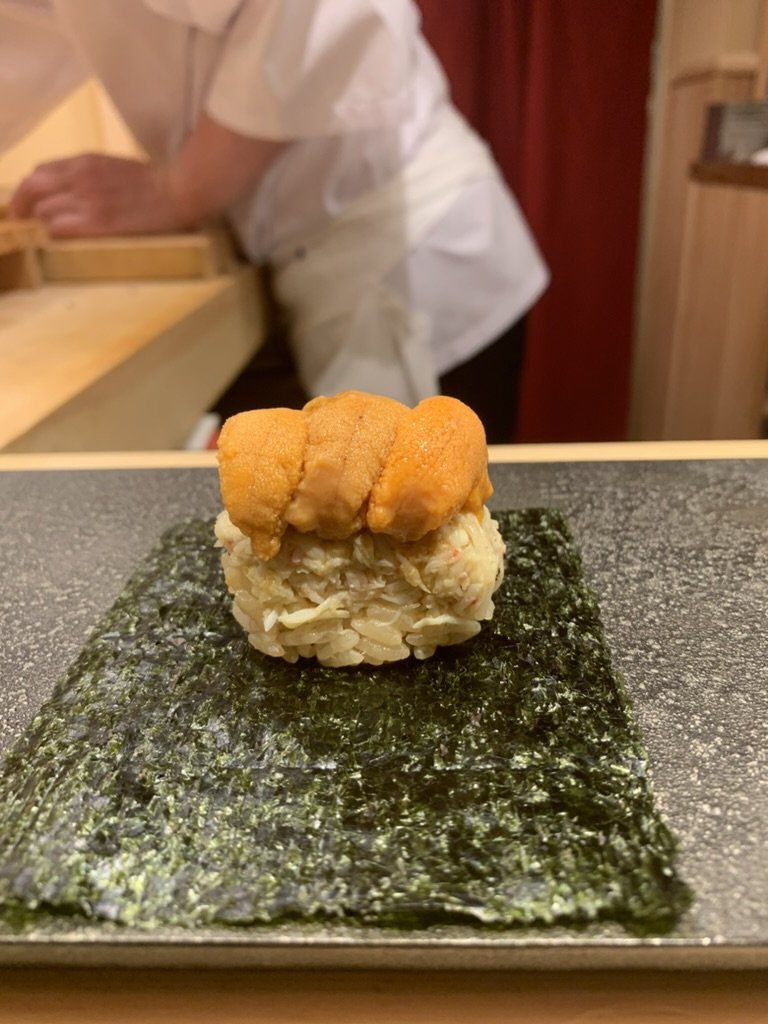 A mound of crab meat topped with sea urchin on a sheet of nori, to roll by hand